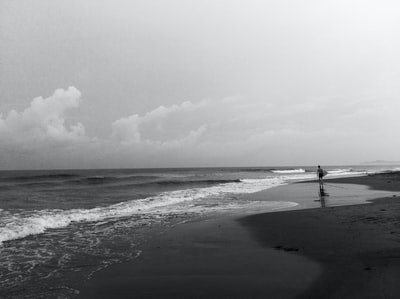 灰度摄影的人站在海滨
